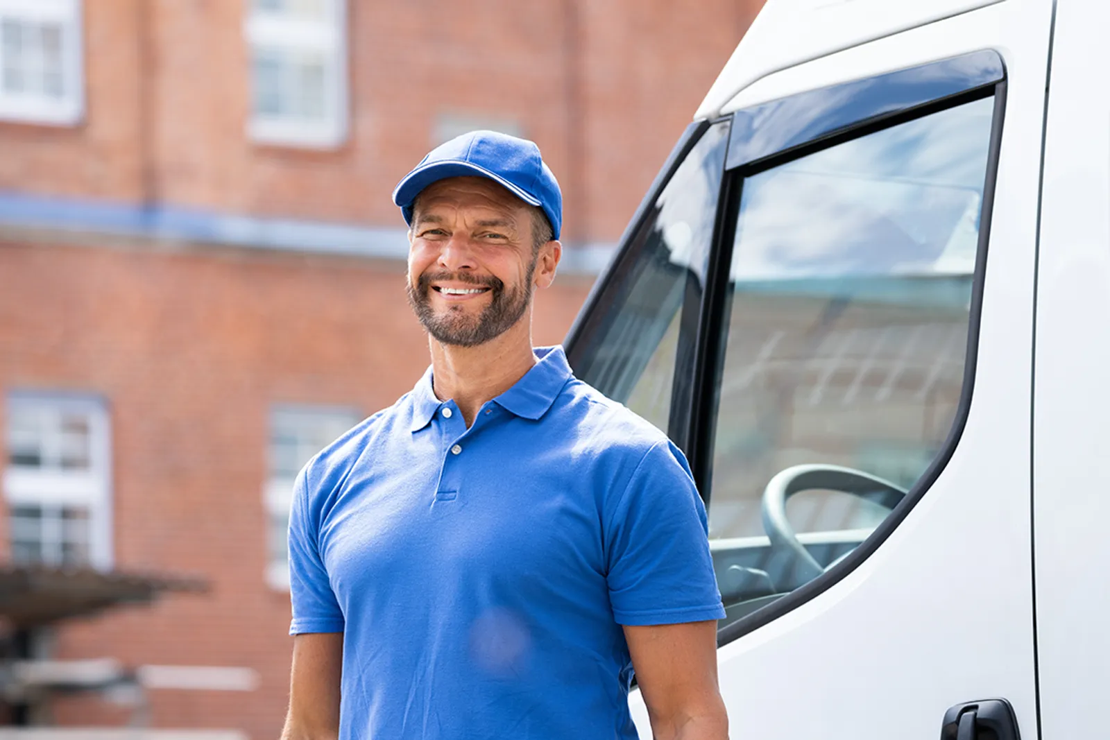 Contractor standing beside his work van outside a brick building
