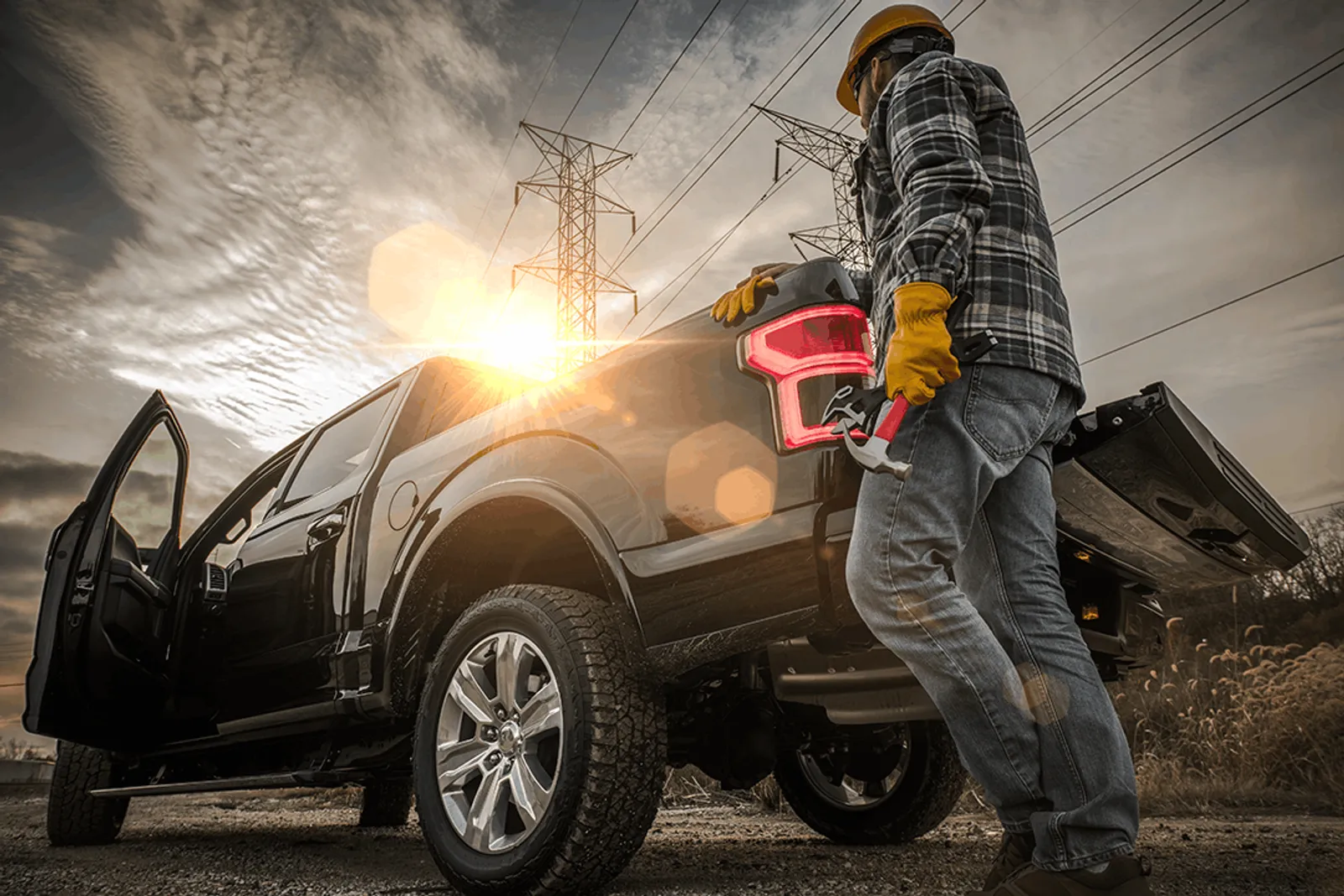 Contractor loading tools into a pickup truck at sunset